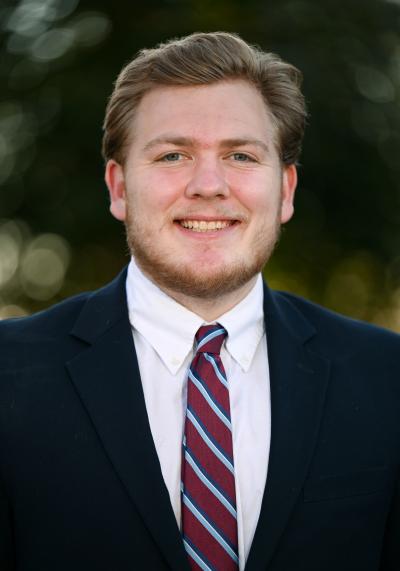 Profile image of Jacob Neuman in a blue jacket and red striped tie.