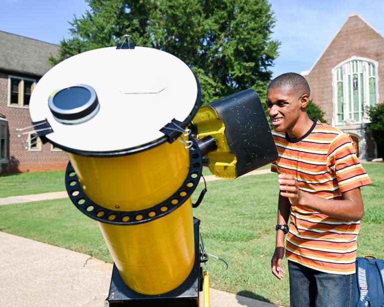 Student looking at a telescope 