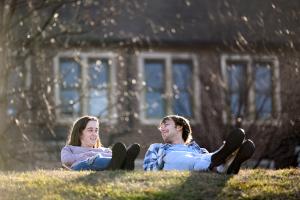 Two students sitting on a grassy hill on a sunny day