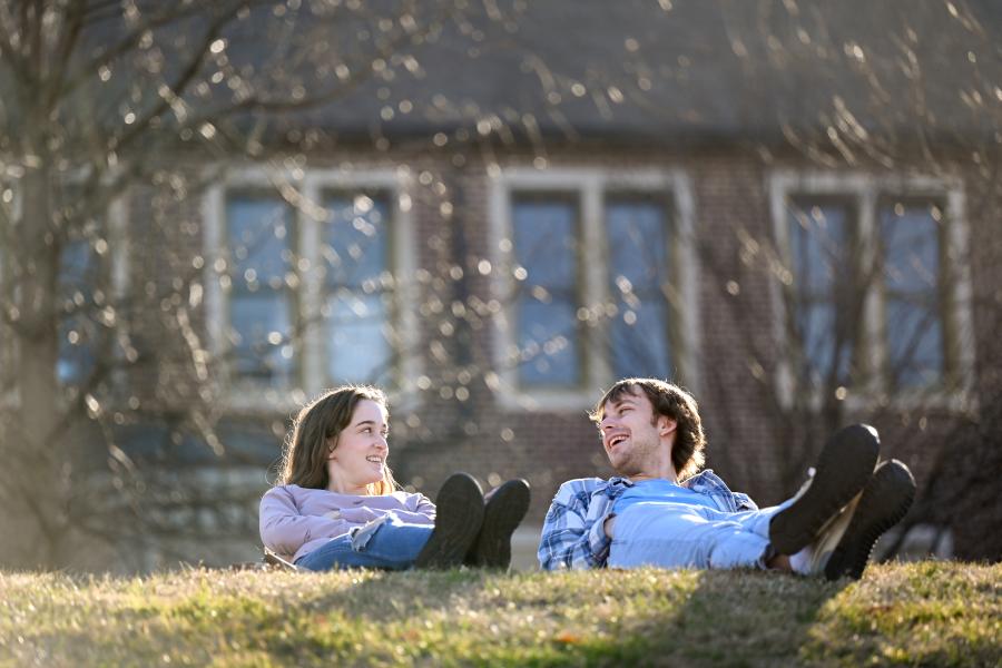 Two UTC students laying on the grass talking to each other