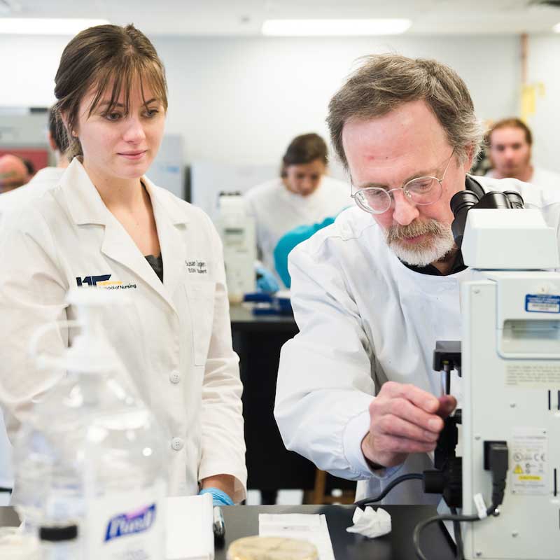 Teacher using microscope with student