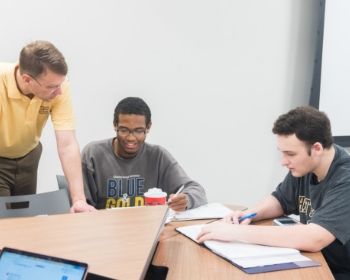 GRE Test Tile 3 Teacher at desk with 2 students