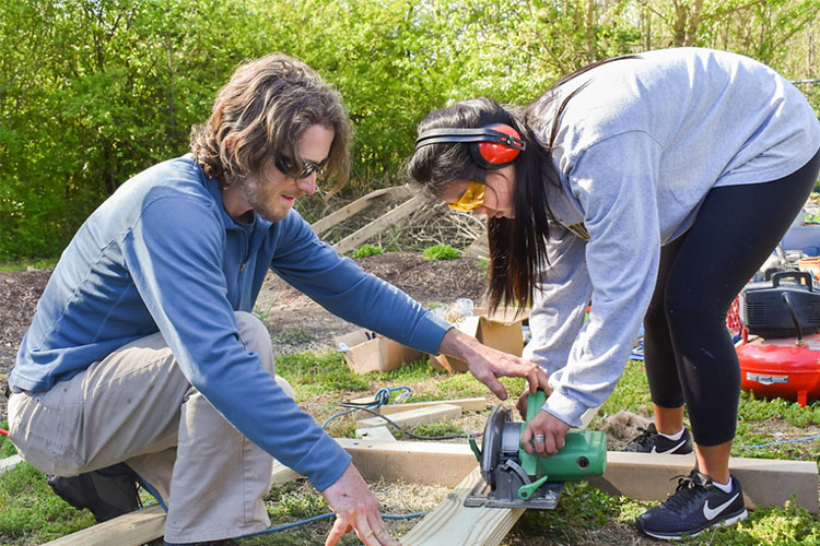 Man and woman using power tools to cut wood