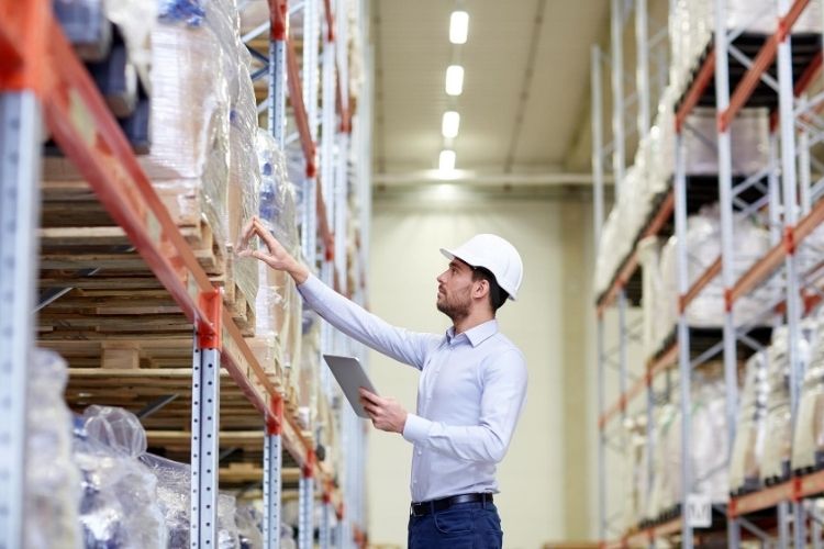 A man standing in a warehouse examining a shelf contents.