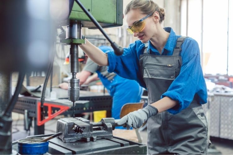 A woman metal worker operating a drilling machine