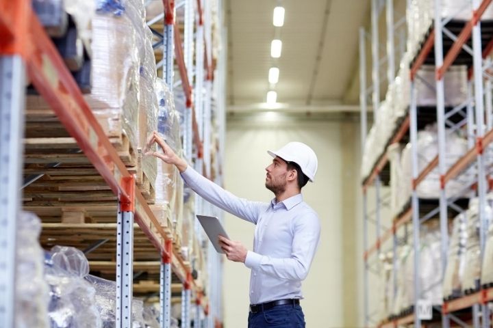A man inspecting containers in a warehouse.