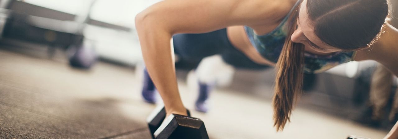 A woman doing push ups with dumbbells