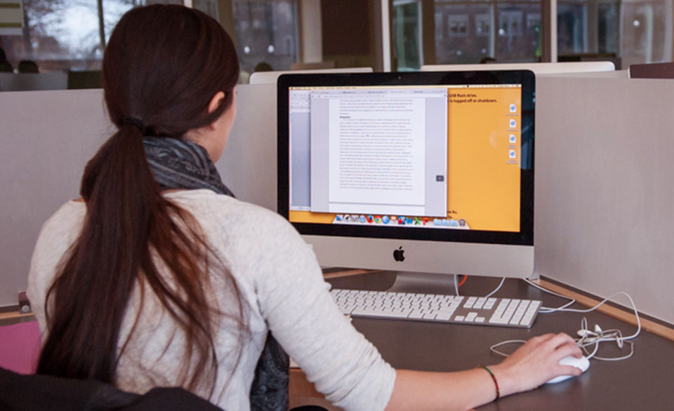 Female student sitting in front of macbook in library