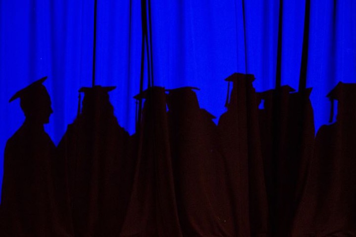 Shadow of students graduating on blue curtain