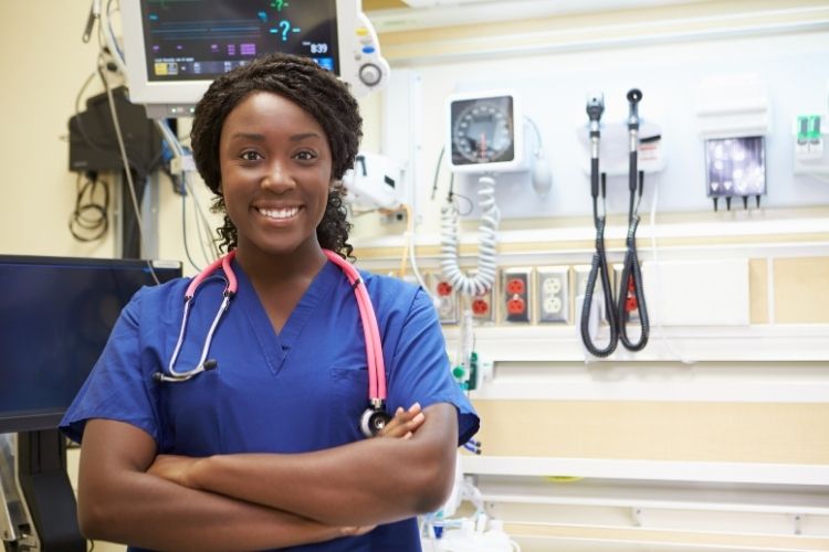 A nurse standing with her arms crossed smiling. She is wearing a stethoscope 