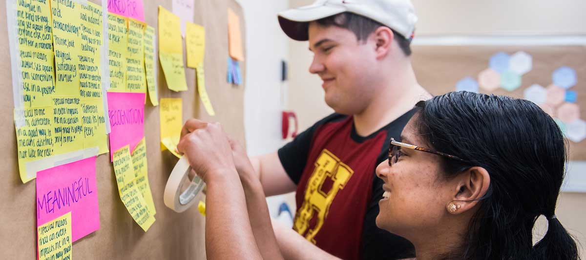 Man and woman posting note to bulletin