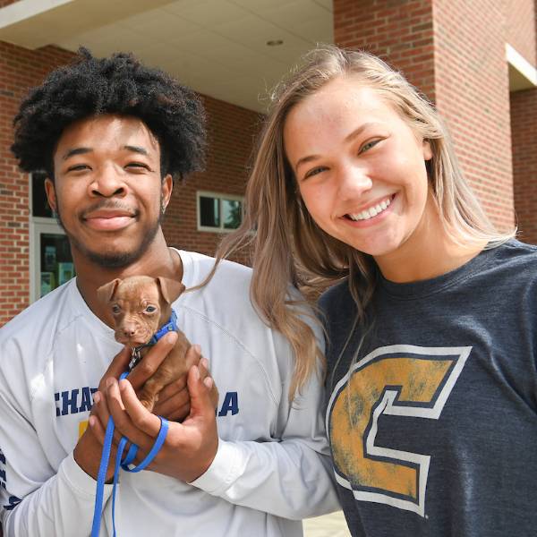 Two students with a tiny puppy