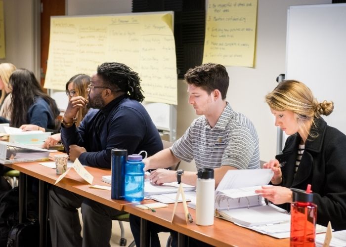 Students sitting in a classroom with PostIt notes behind them