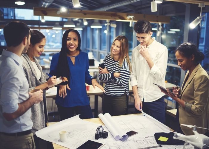 A group of professionals standing around a table discussing project plans