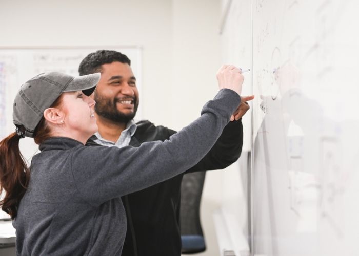 PMP Exam Prep Participants working a critical path formula on a white board