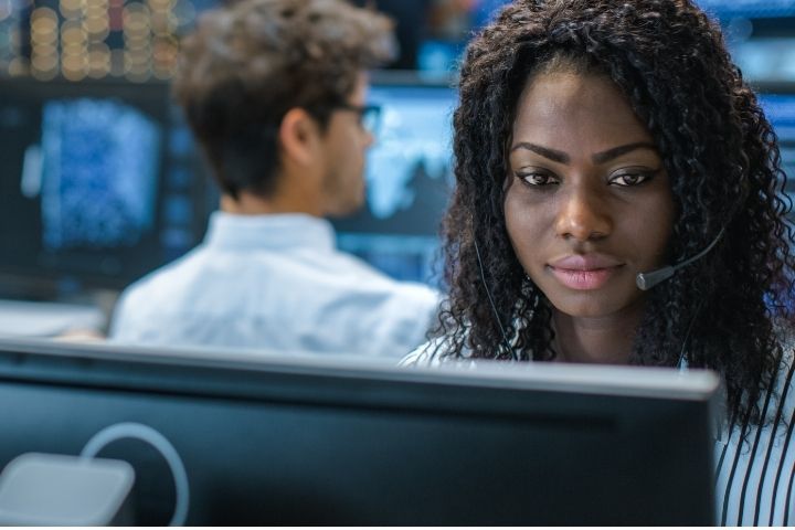 A customer service representative sitting at a desk with a computer while wearing a headset