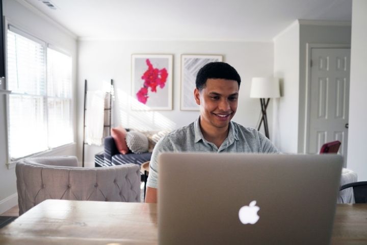 A man sitting at a desk while looking at a MacBook