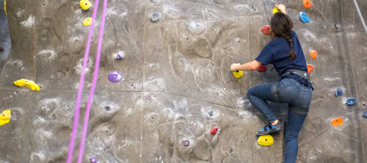 student climbing rock wall