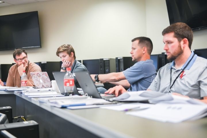 A group of students sitting in a class discussing among each other.