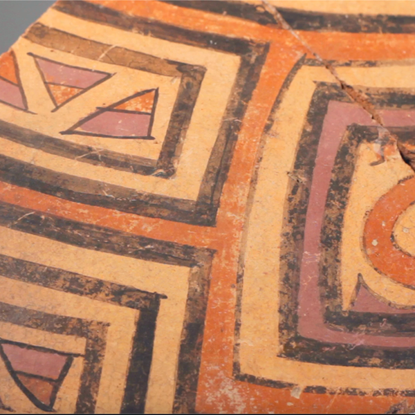 Pre-Columbian ceramic sherd with decorative lines in black, purple, and red slip.