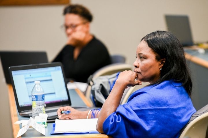 A woman sitting in a classroom with a laptop open next to her