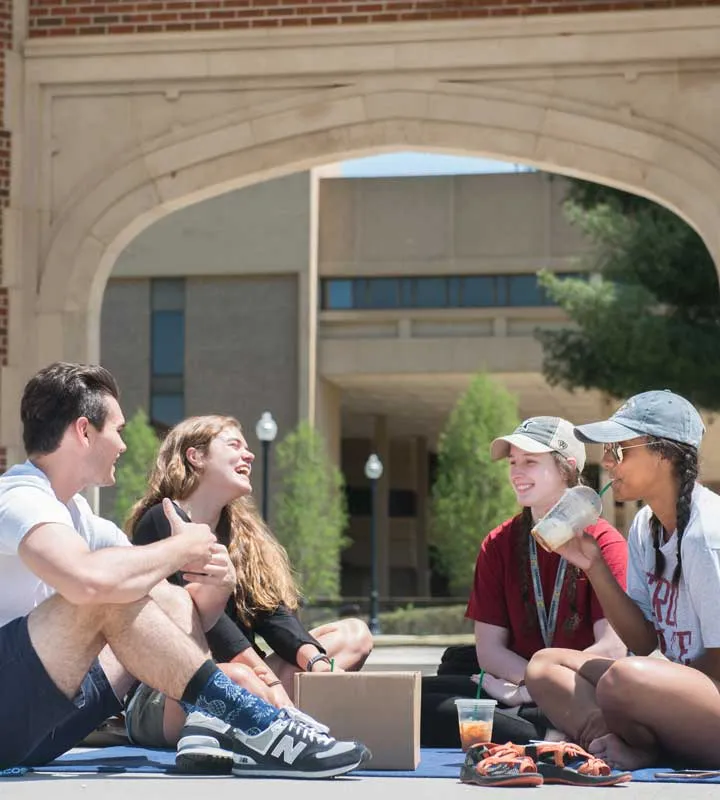 four students sitting below chamberlain pavilion