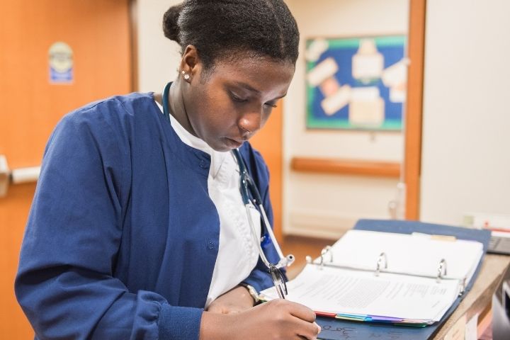 A nursing student working on charts at a hospital