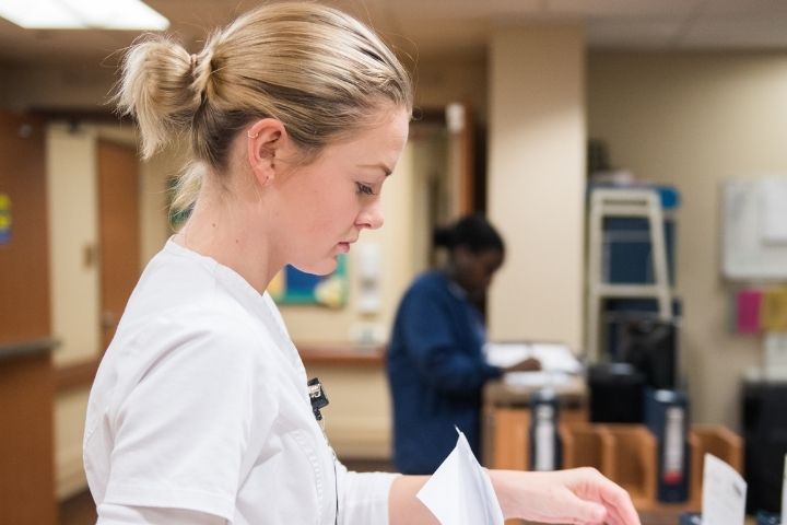 A nursing student working on charts at a hospital