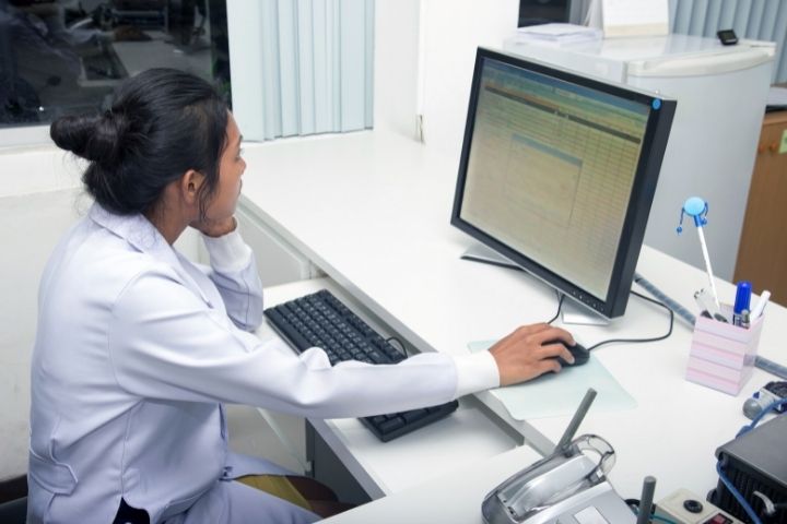 A medical professional sitting at a desk while looking at a computer screen