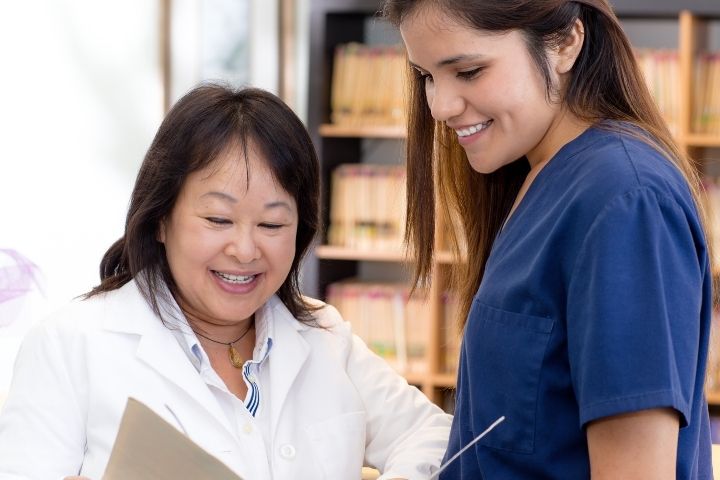 Two medical professionals talking with one another as they review a patient's chart