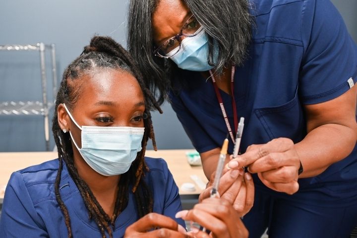 Pharmacy technician student learning how to fill a syringe