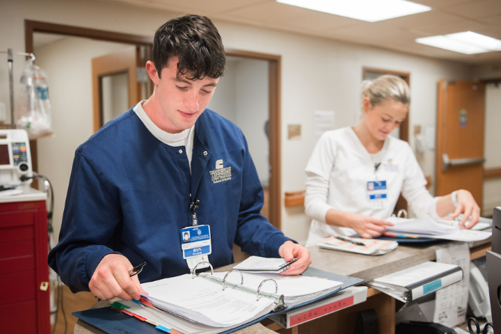 male nursing student looking at a binder male nursing student looking at a binder