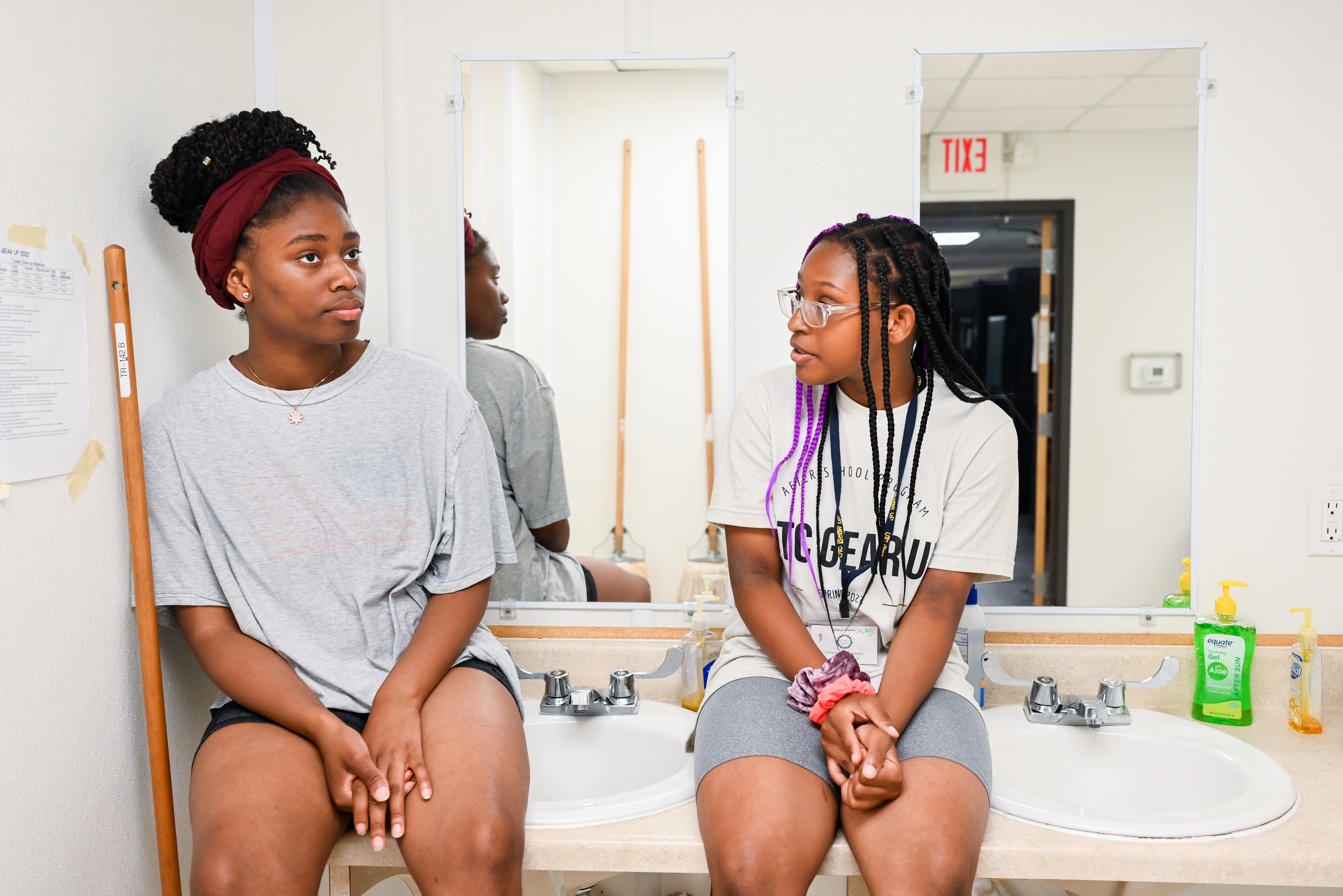 Two students talking on top of bathroom sink