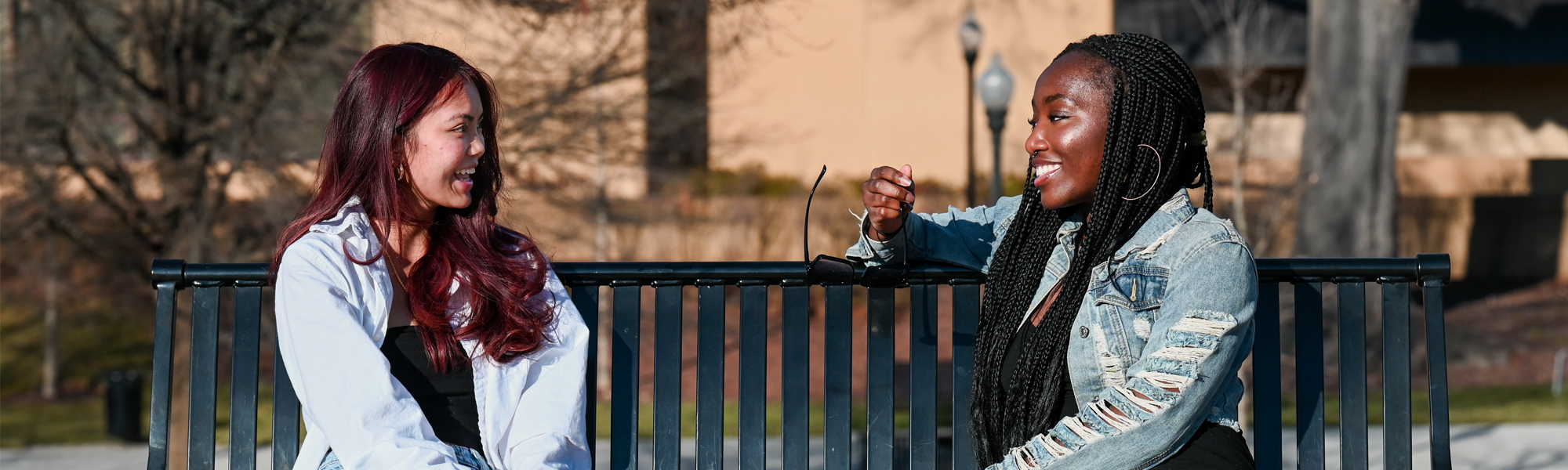 Two female UTC students sitting on a bench on a sunny day