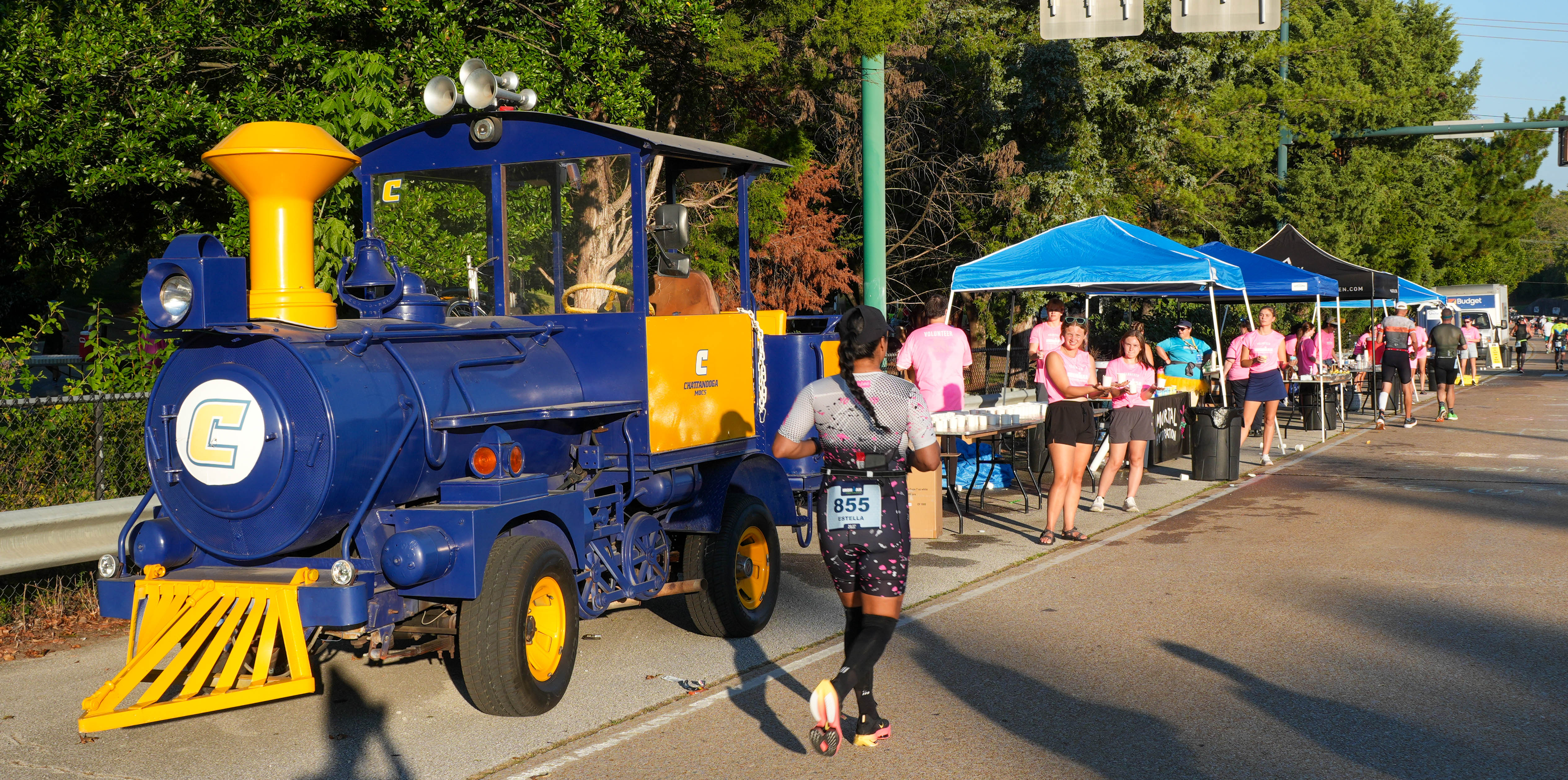2025 Chattanooga Ironman competitor runs past blue and yellow UTC train