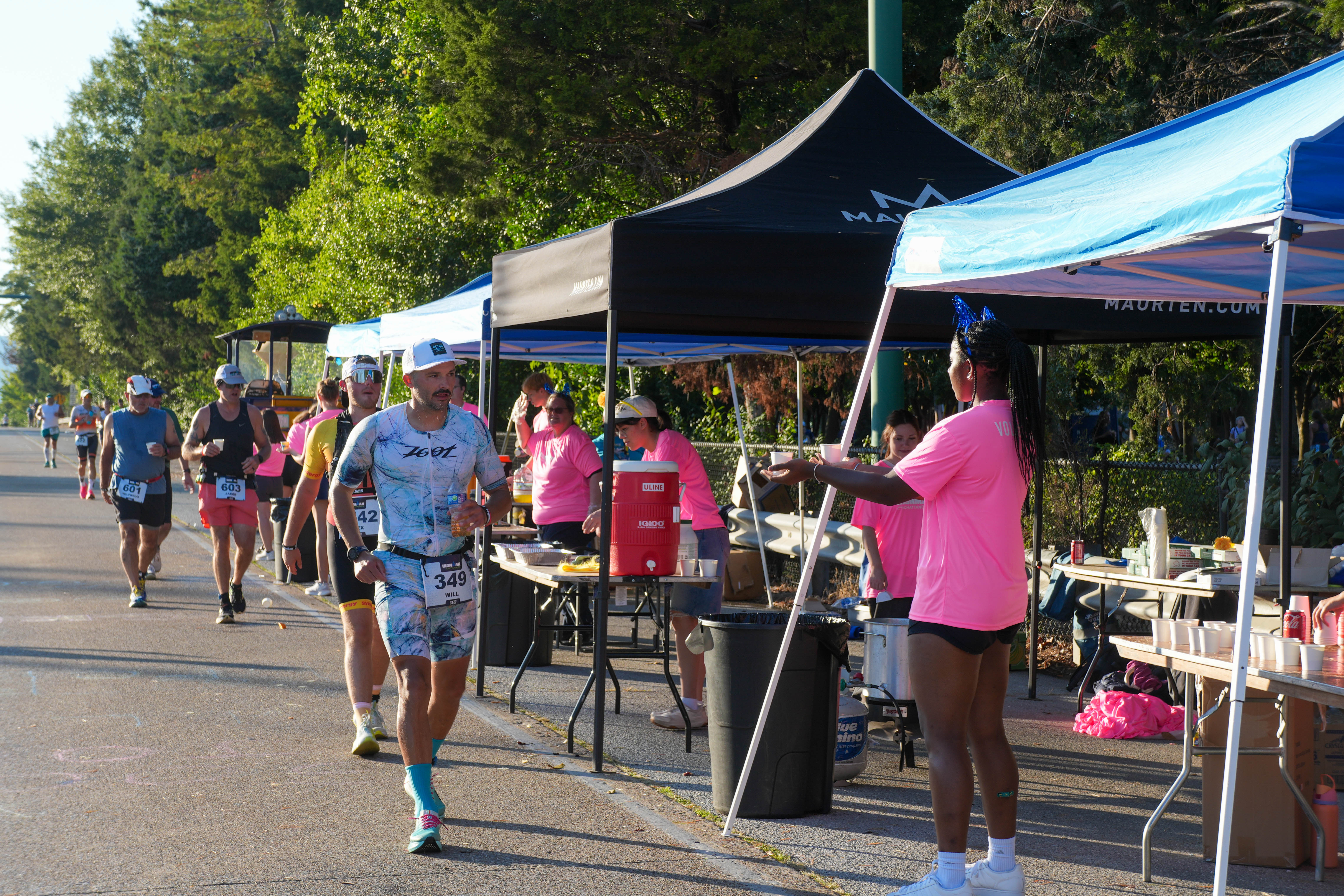 Students in pink shirts handing water to 2025 Chattanooga Ironman competitors
