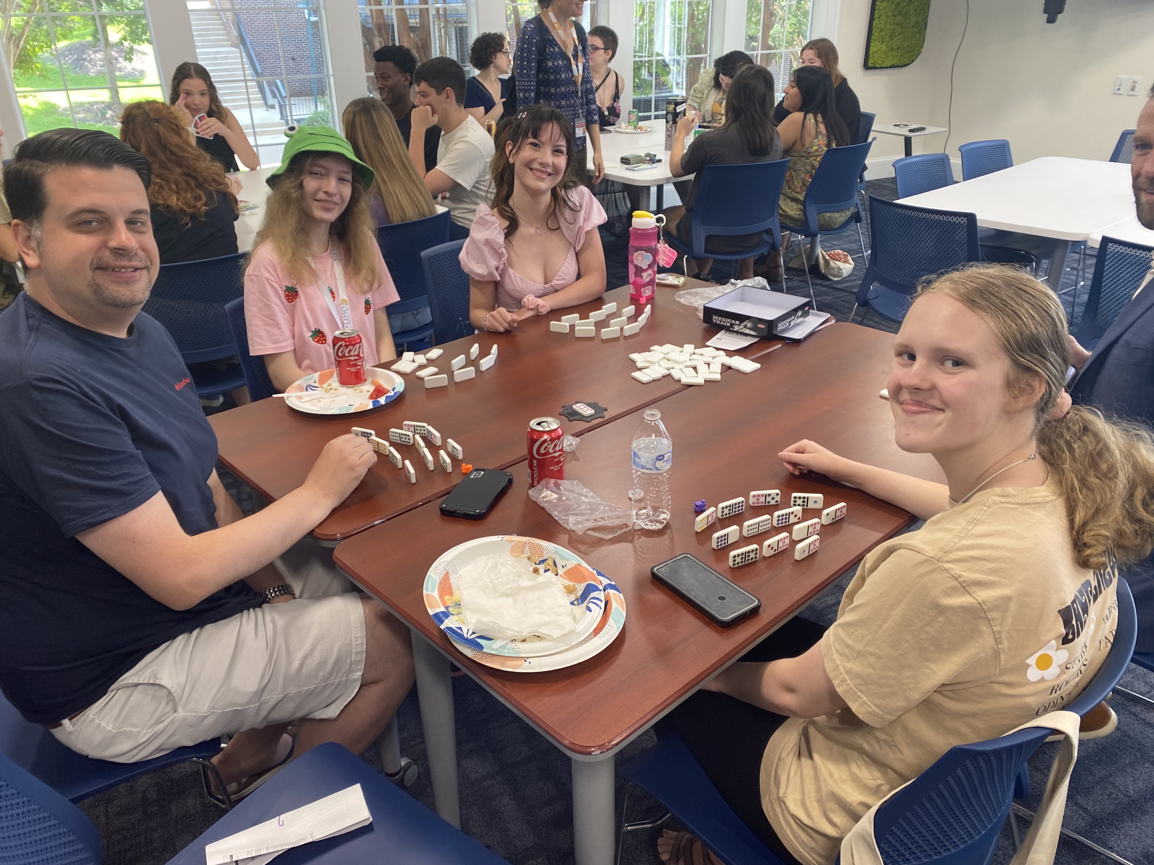 Students gathered around a table playing dominoes and talking during an A&SRC community event