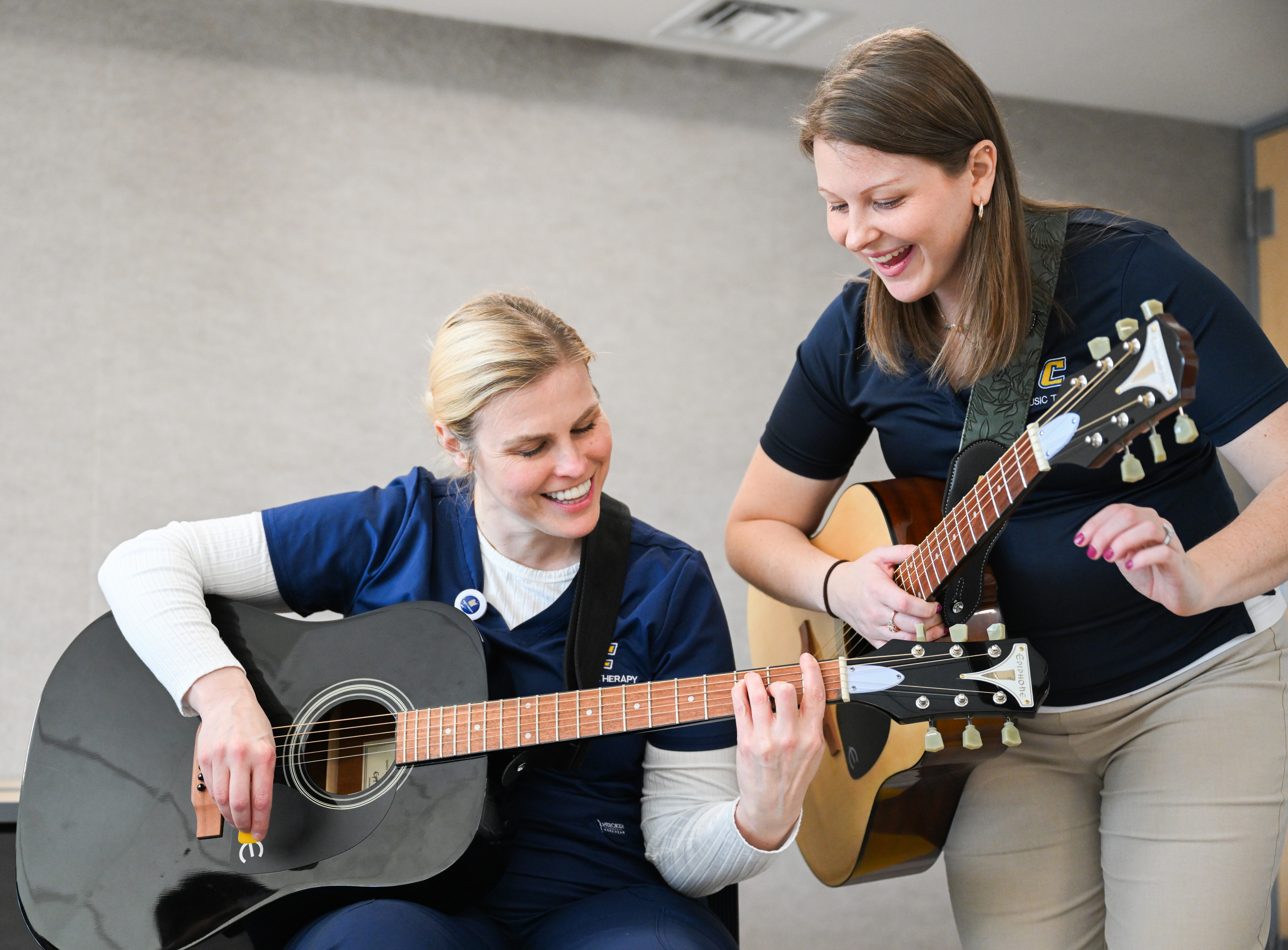 Two ladies holding guitars and smiling. 