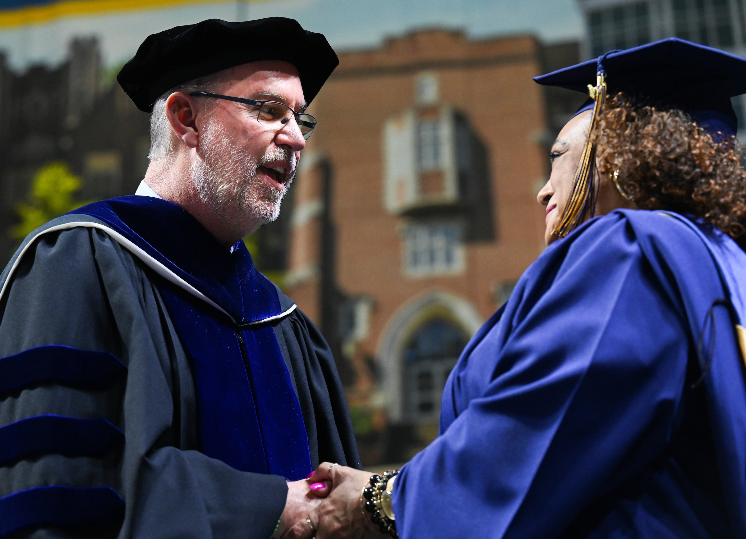 RCOB Dean Robert Dooley shakes hands with a graduate as they cross the stage at commencement.