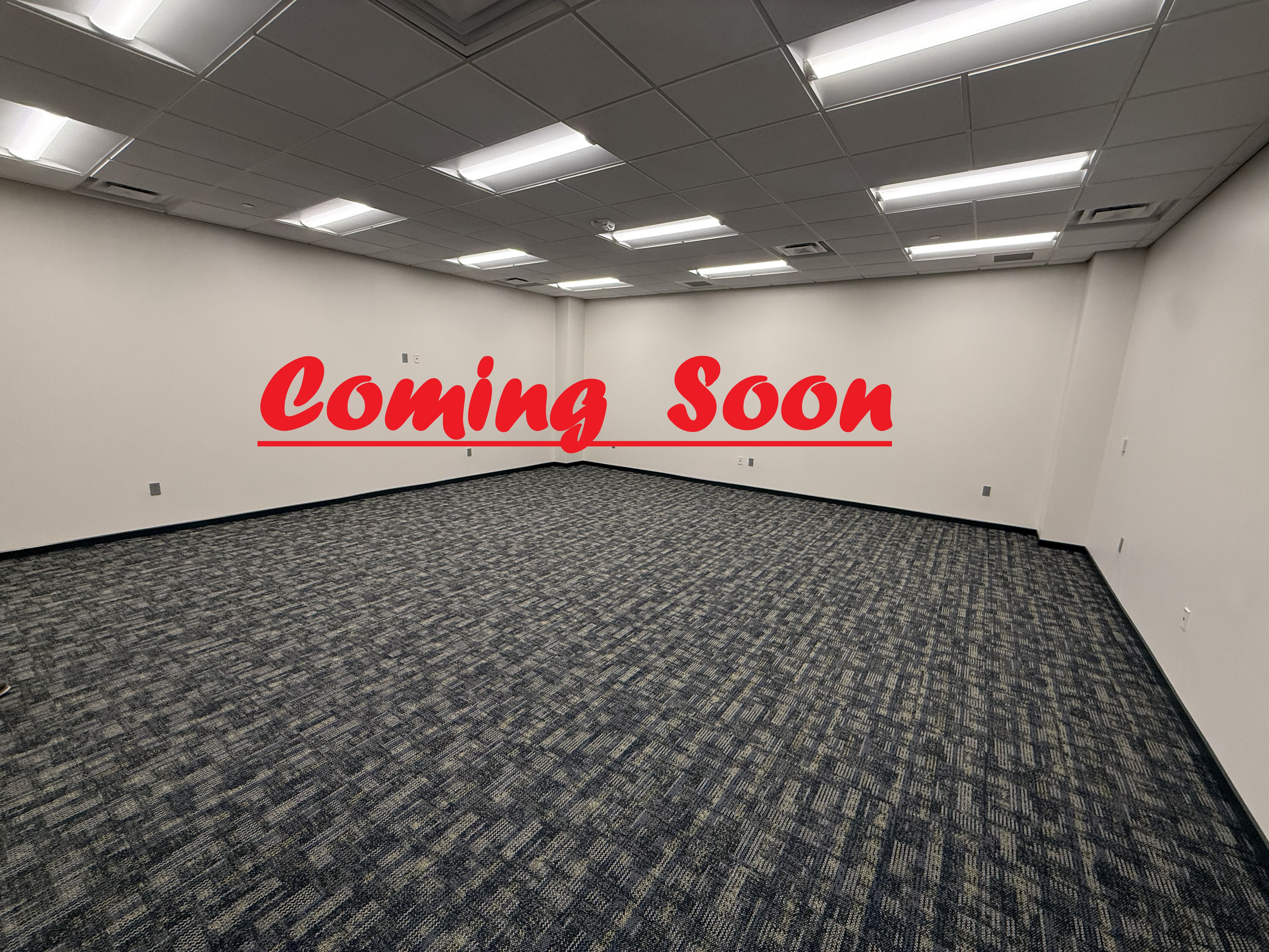 Pictured is Room 304 in the University Center. The space is empty with only the walls and carpet being shown. The words "Coming Soon" have been placed on the image. 