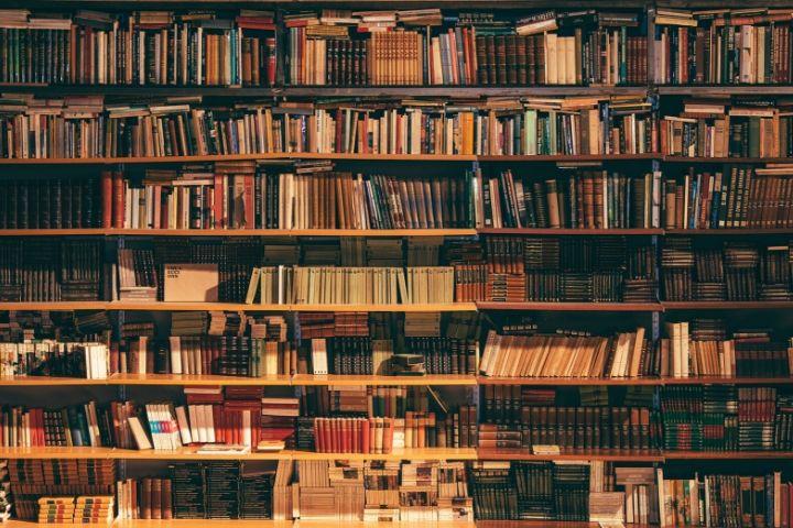 A dark picture of multiple shelves filled with older books