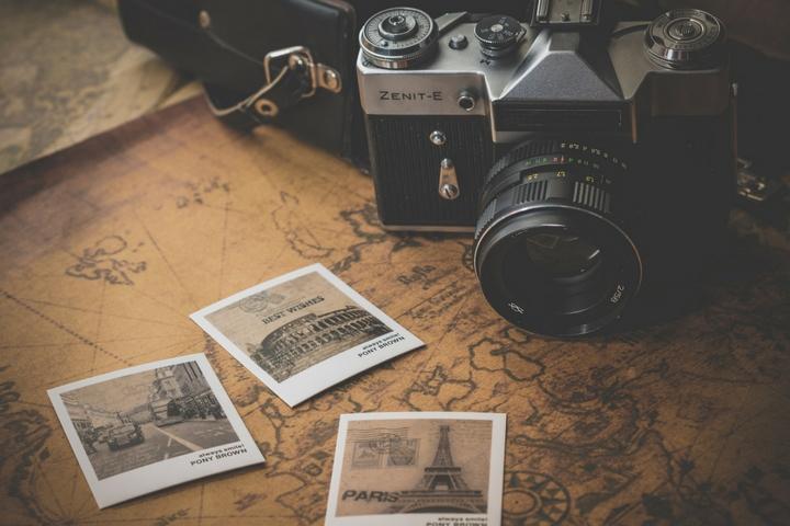 A polaroid camera with three polaroids sitting in front of it on an old map