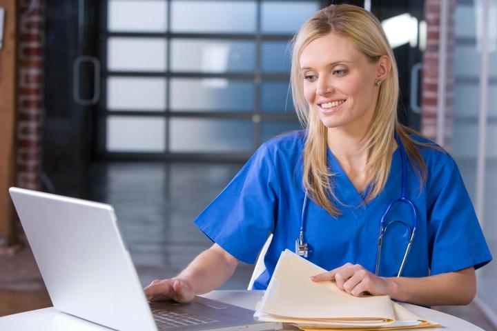 doctor holding files and on her computer