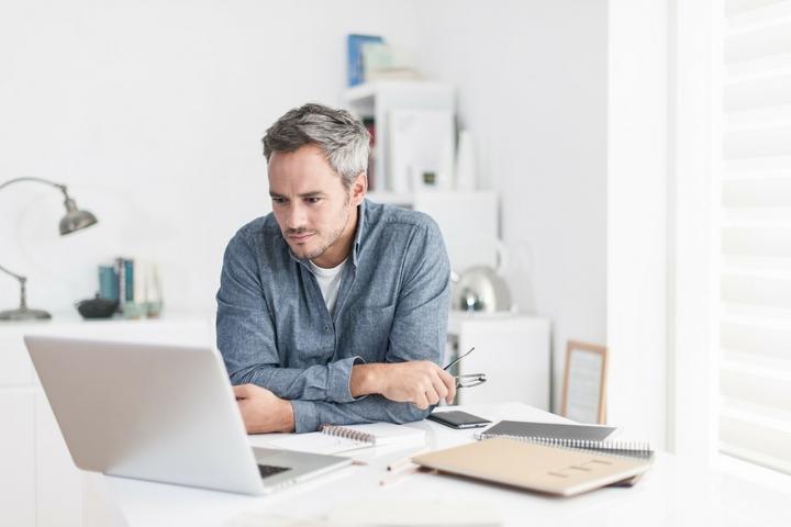 Man at desk, looking at laptop