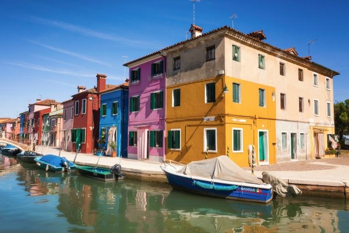 colorful houses sitting on the water with boats lined up along all sides