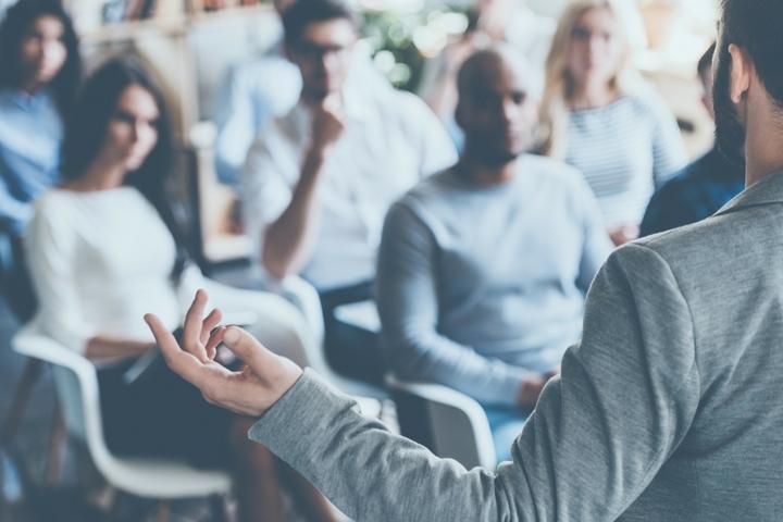 A man standing in front of group of people giving a lecture