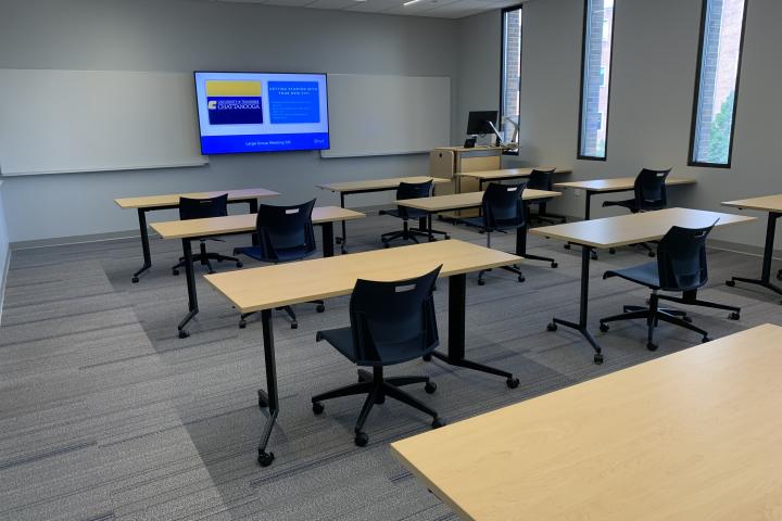 Lupton Hall's Large Meeting Room, containing multiple tables, chairs, and monitor