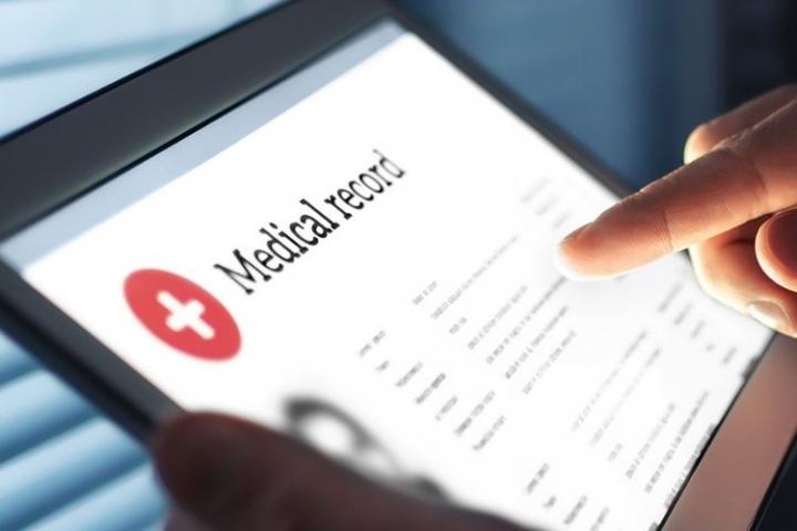 A person holding a tablet that has a window open that is titled Medical Record