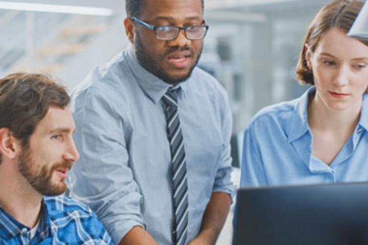 Three workers around a computer