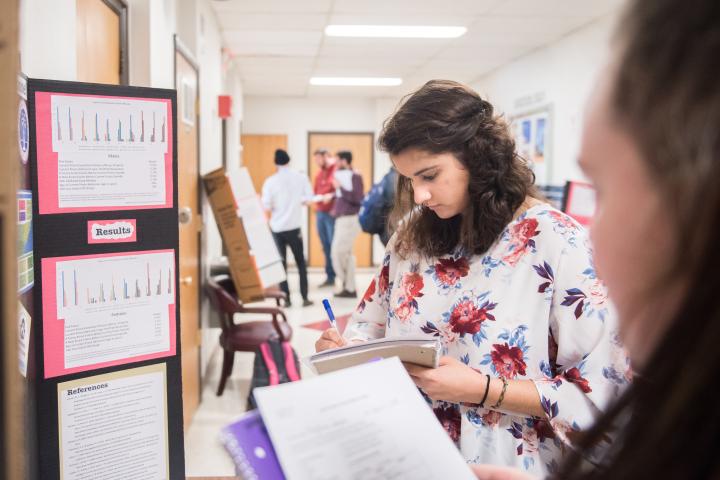 Sociology students make notes about a research presentation kiosk